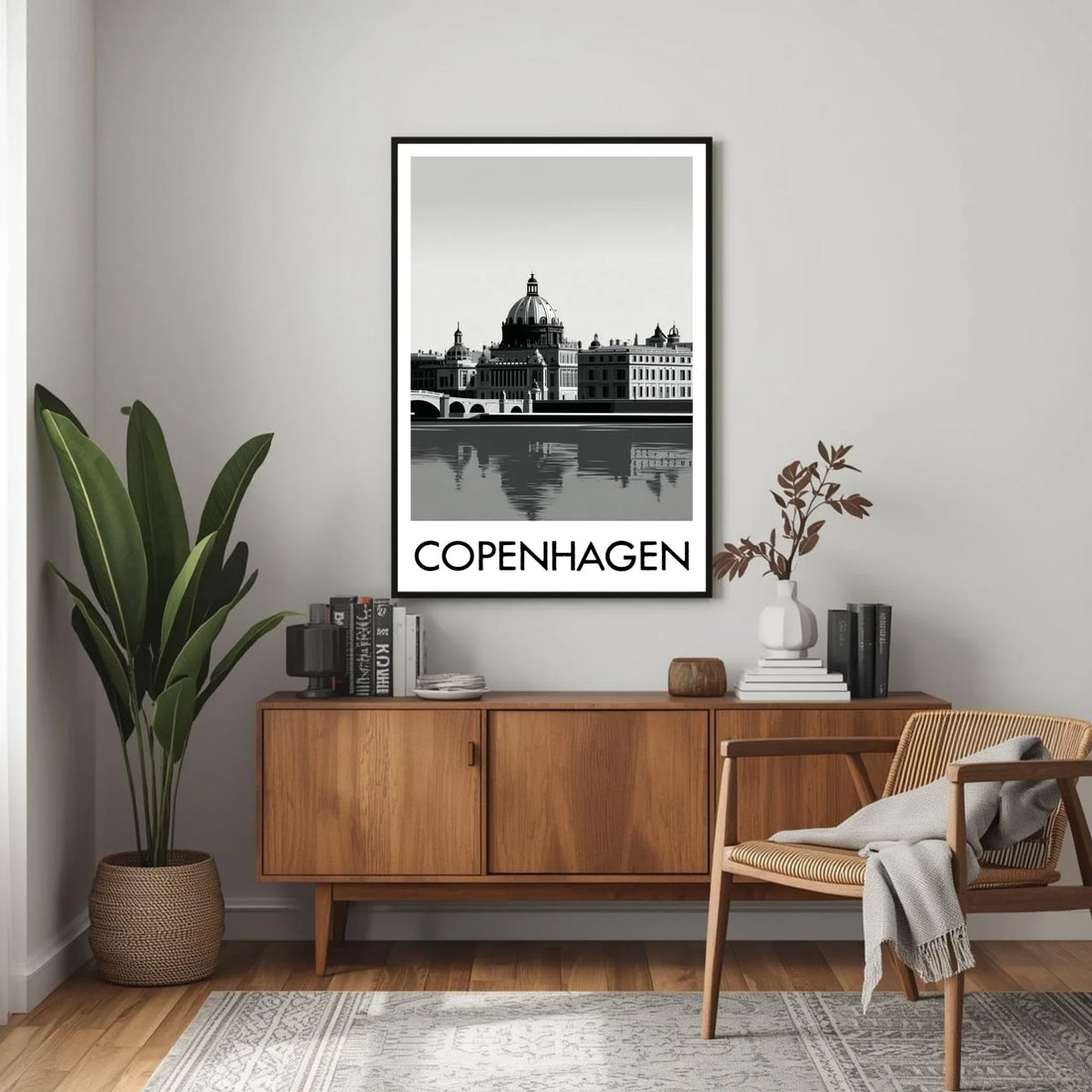 Framed artwork of Copenhagen on a wall above a wooden sideboard with decor items.