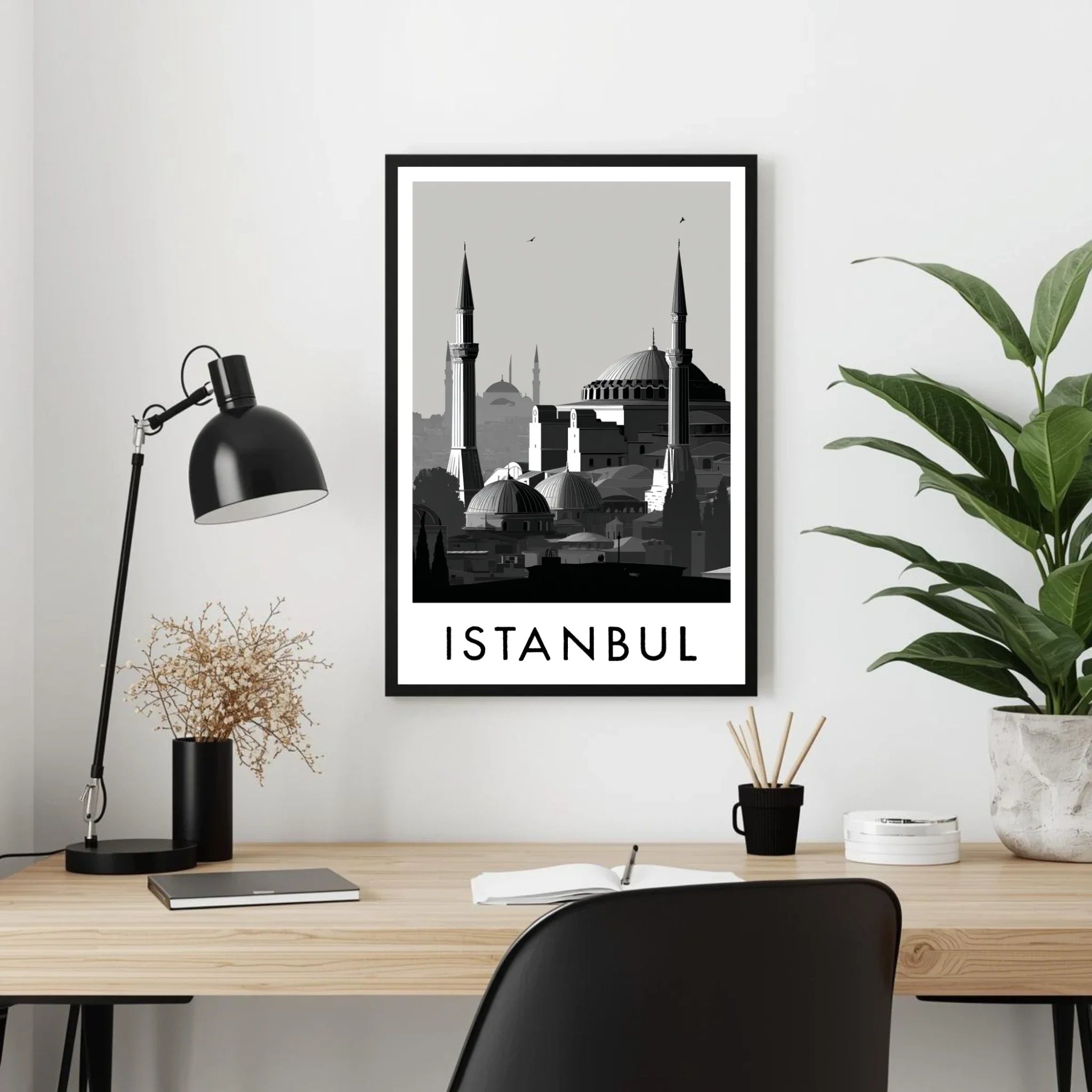 Framed artwork of Istanbul on a wall above a desk with a lamp and plant.