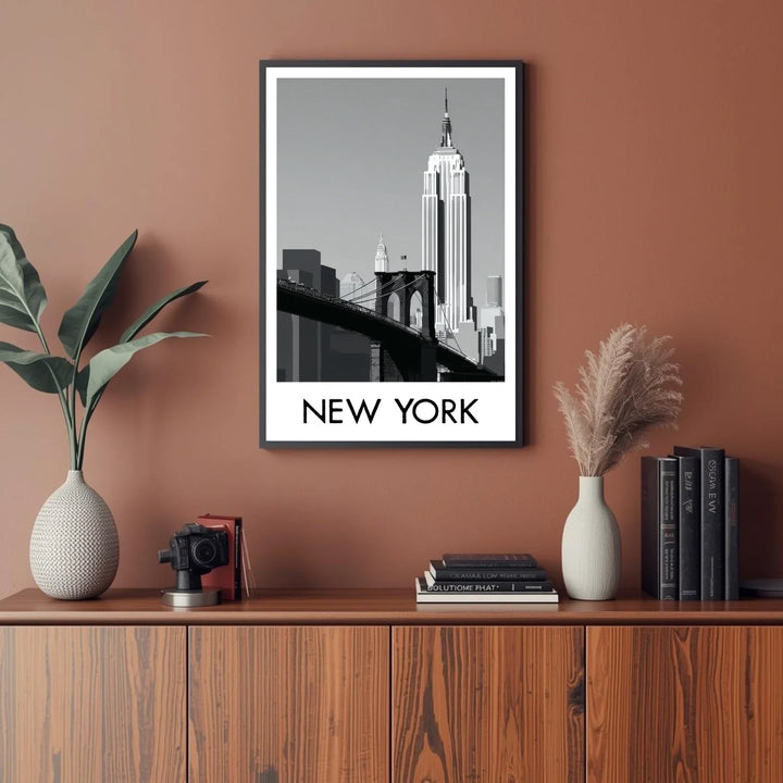 Framed New York cityscape print on a wall above a wooden cabinet with decorative items.