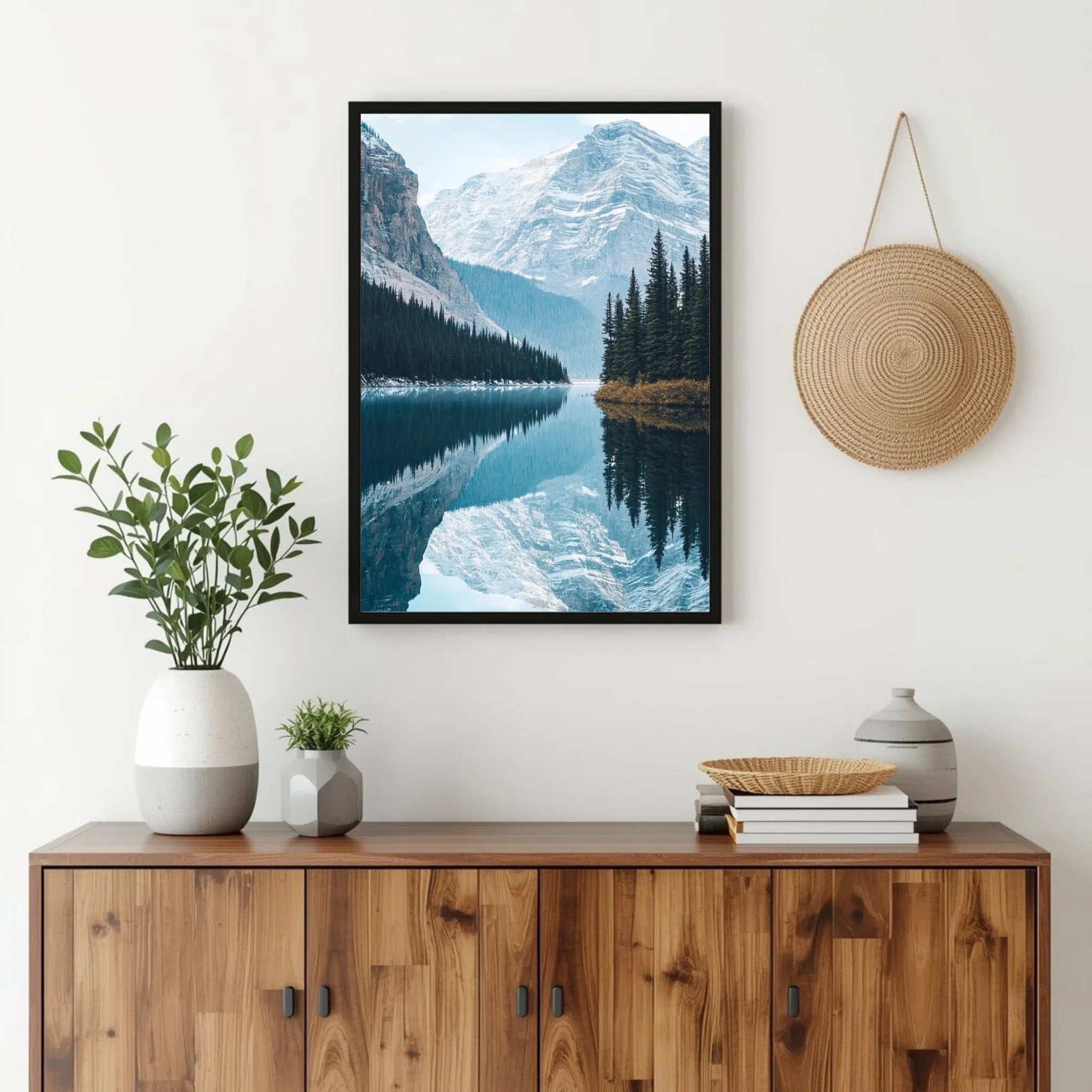 Framed mountain landscape print above a wooden cabinet with decorative items.