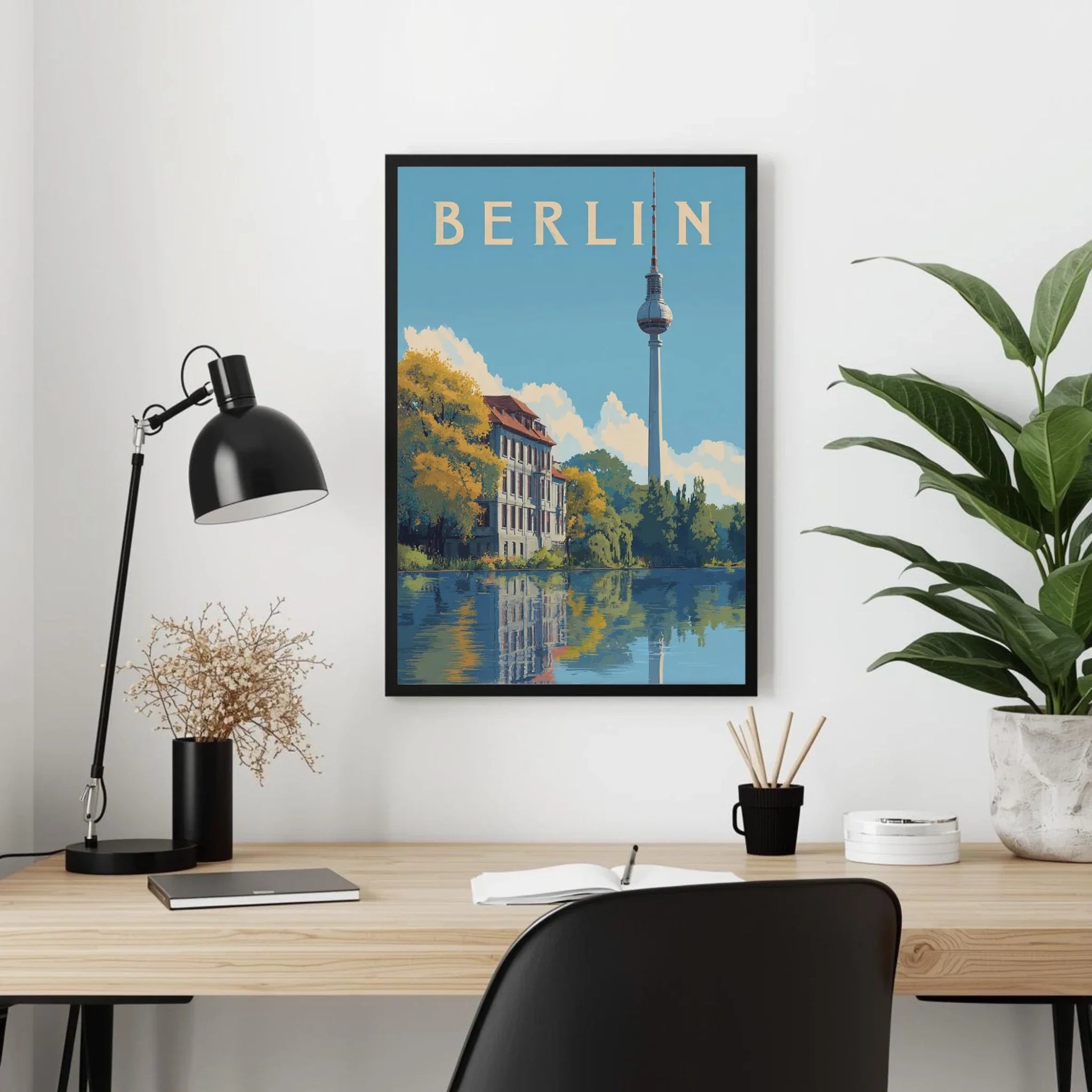 Framed Berlin poster on a wall above a desk with office items.