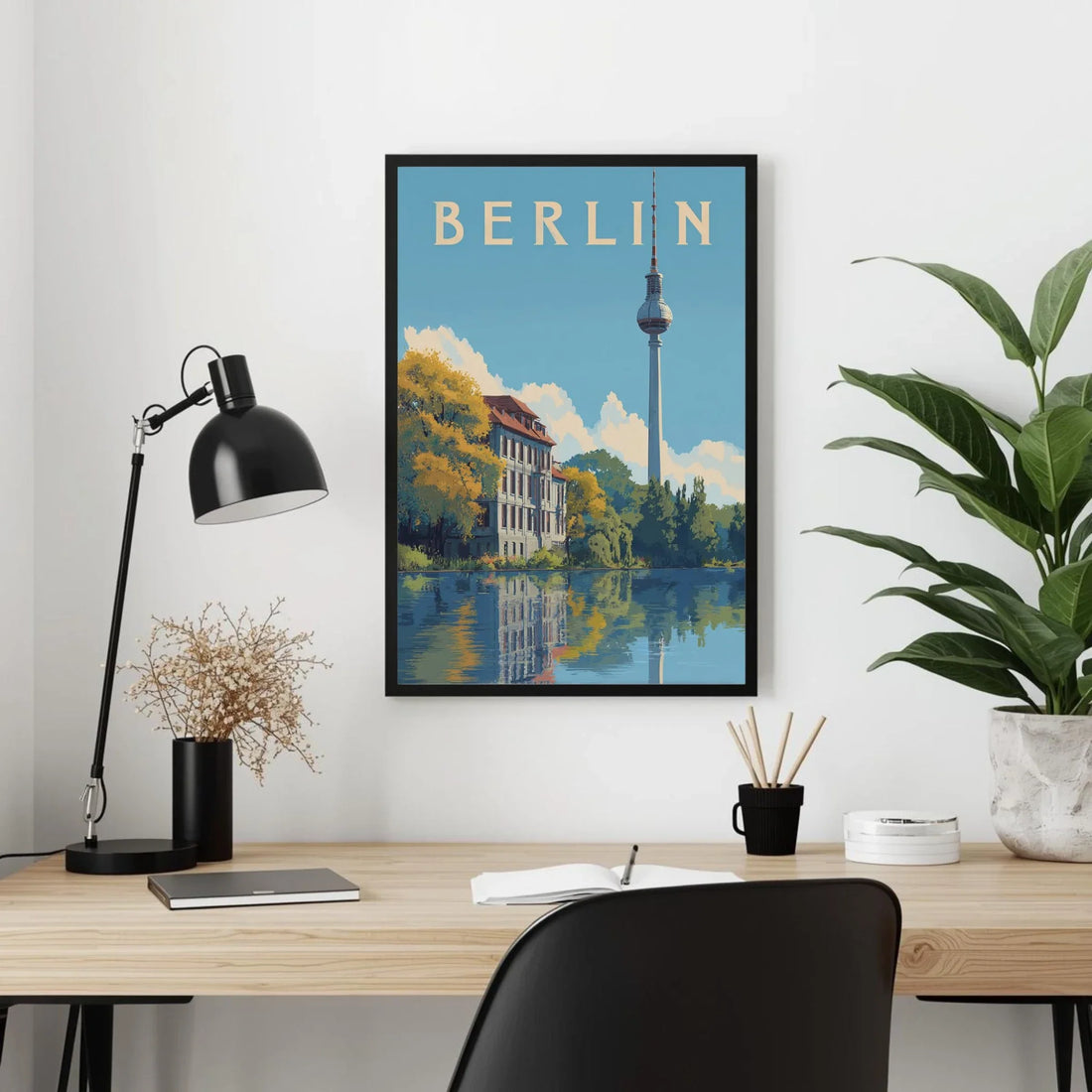 Framed Berlin poster on a wall above a desk with office items.