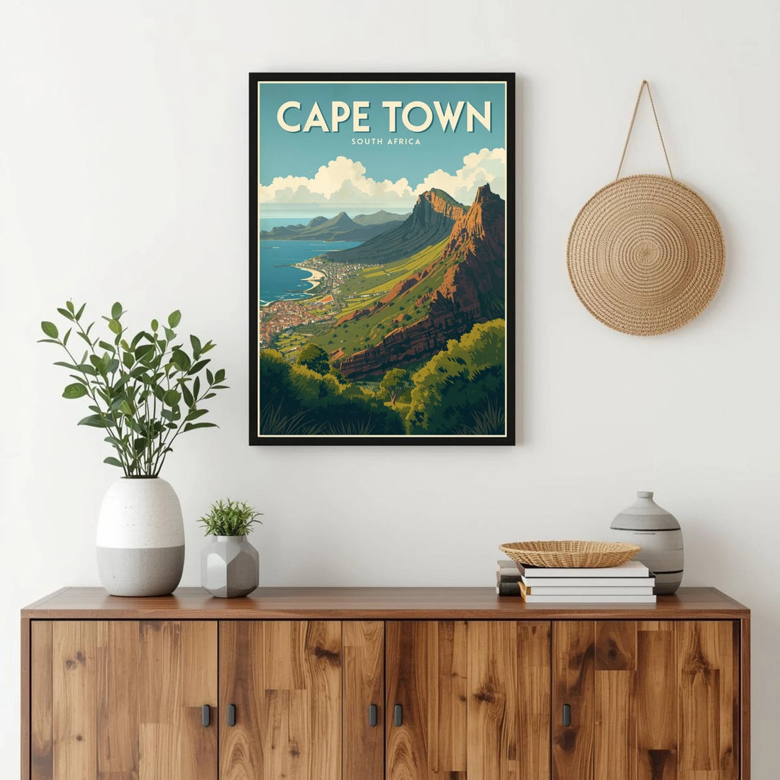 Framed poster of Cape Town on a wall above a wooden cabinet with decor items.