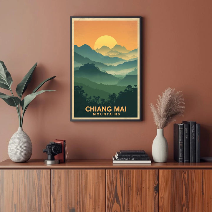 Framed poster of Chiang Mai mountains on a wall above a wooden cabinet with decor items.