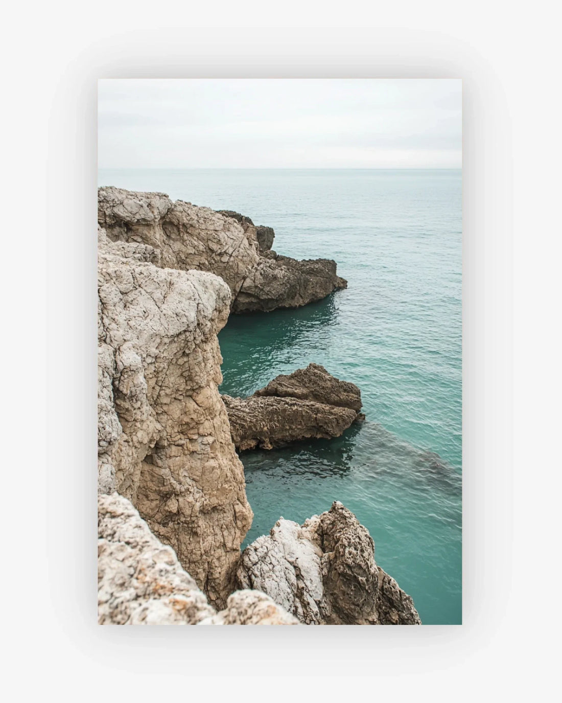 Rocks jutting out into a body of water with a white frame.