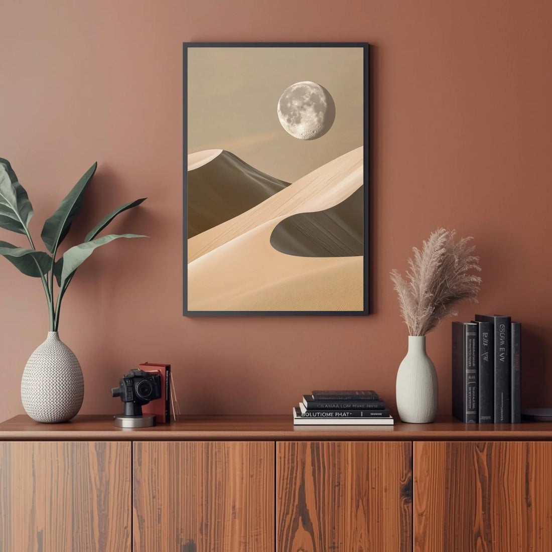 Framed desert landscape art on a wall above a wooden cabinet with decor items.