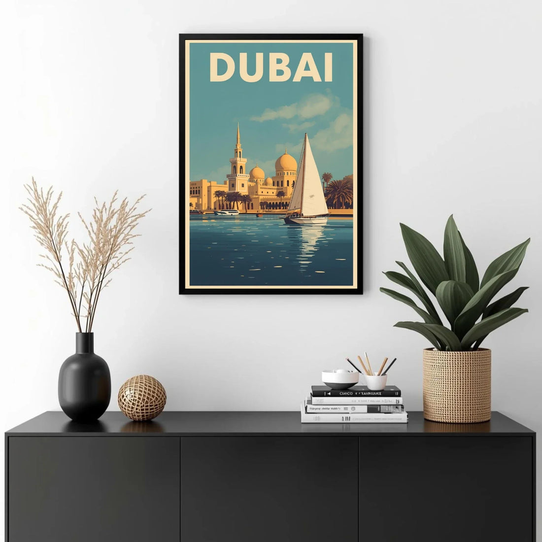Framed poster of Dubai with a sailboat and cityscape, displayed on a wall above a black cabinet with decorative items.