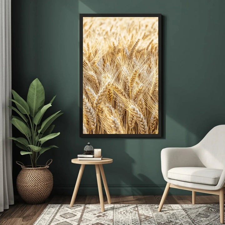 Framed artwork of wheat on a dark green wall with a plant and small table in the foreground.
