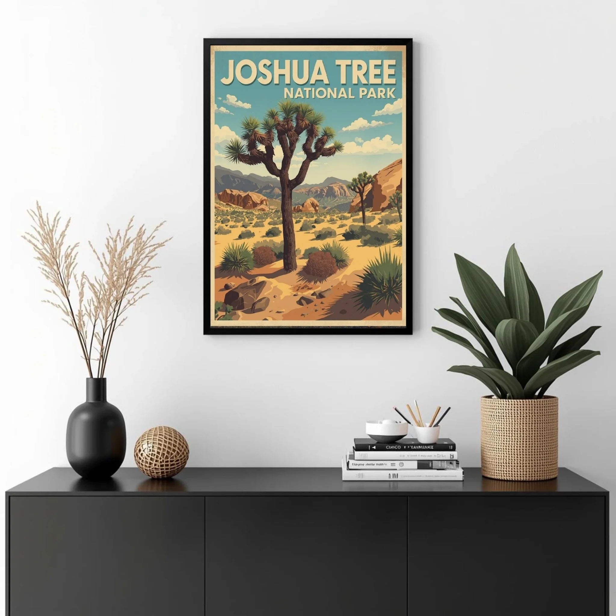 Framed poster of Joshua Tree National Park on a wall above a black cabinet with decorative items.