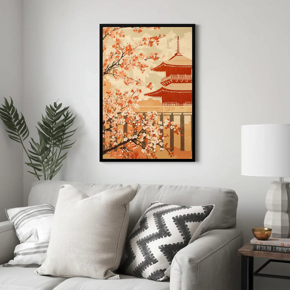 Framed artwork of cherry blossoms and a pagoda on a wall above a sofa with decorative pillows.