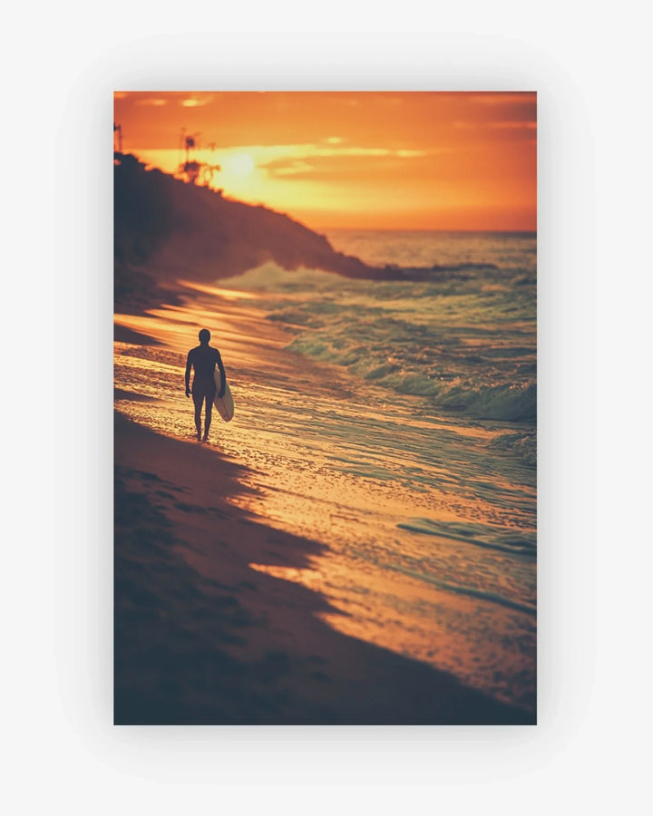 Person walking along a beach at sunset with a surfboard
