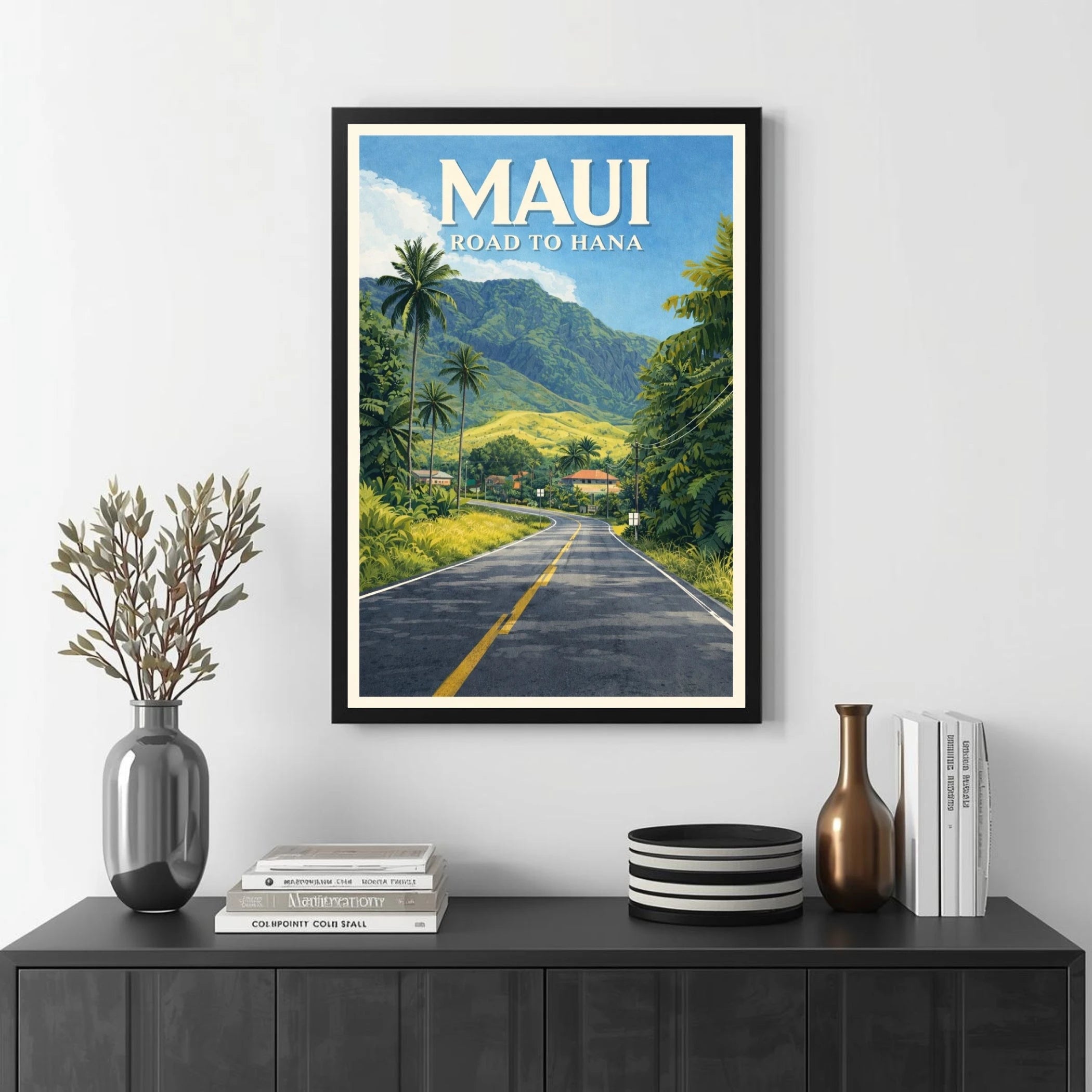 Framed poster of 'Maui Road to Hana' on a wall above a black console table with decorative items.