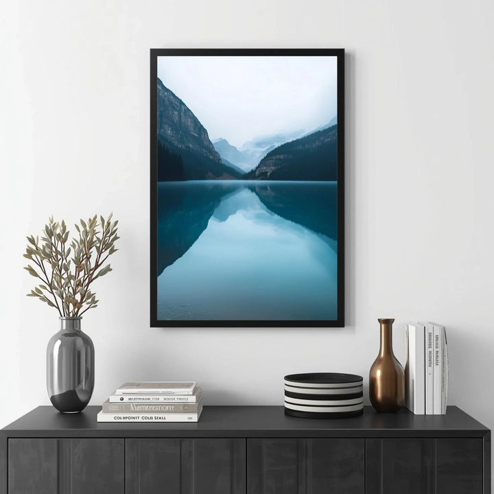 Framed mountain landscape print on a wall above a black console table with decorative items.