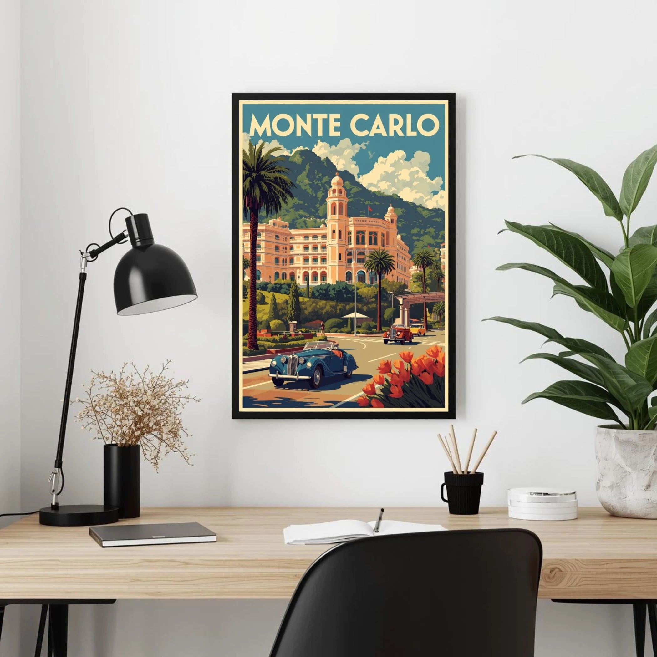 Framed Monte Carlo poster on a wall above a desk with a lamp and plants.