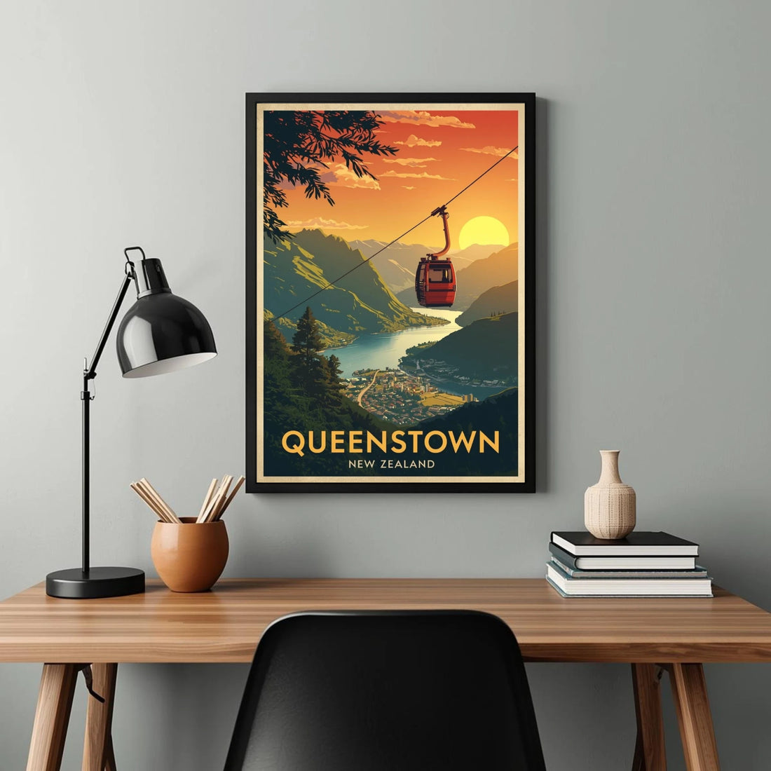 Framed poster of Queenstown, New Zealand on a wall above a desk.