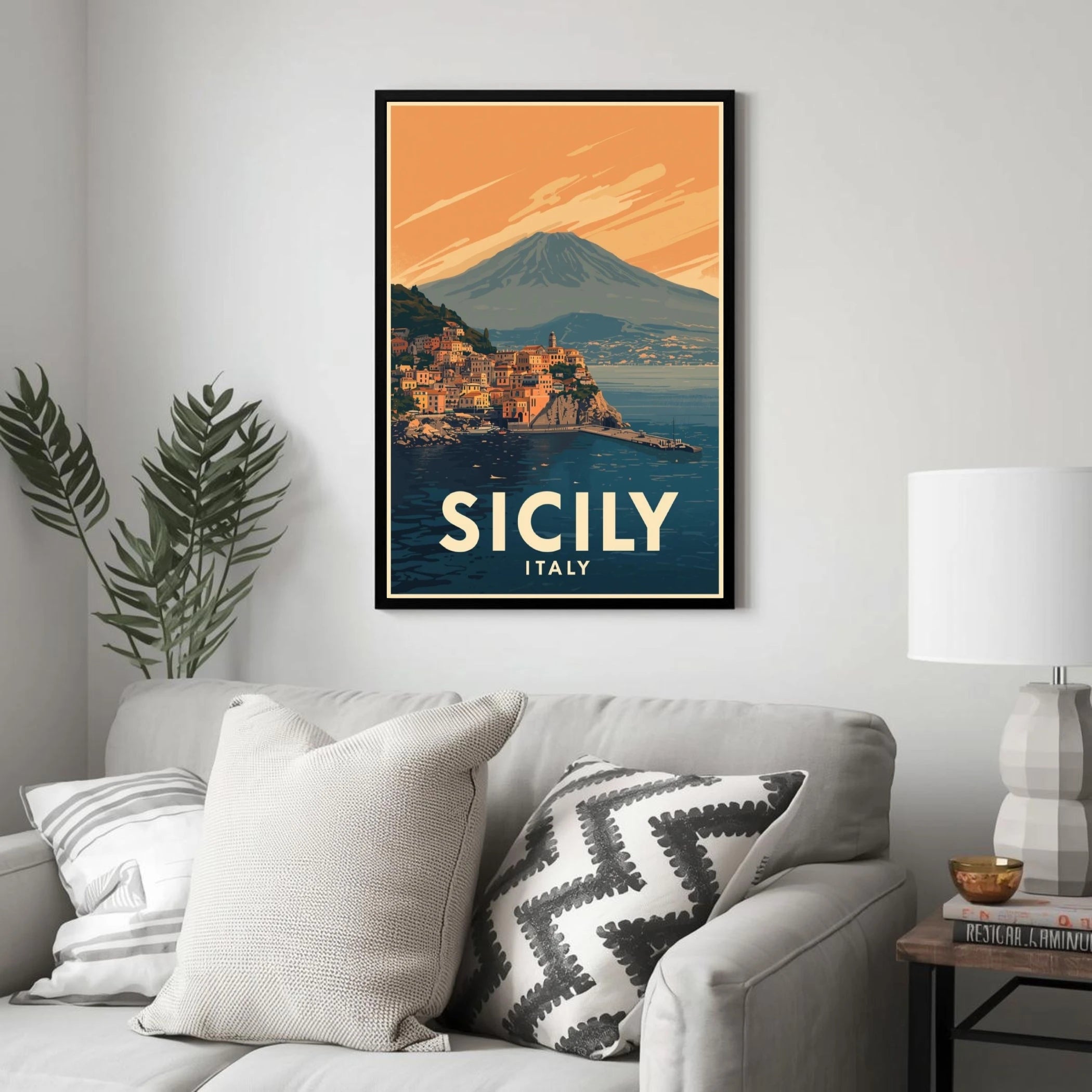 Framed poster of Sicily, Italy on a wall above a sofa with decorative pillows.