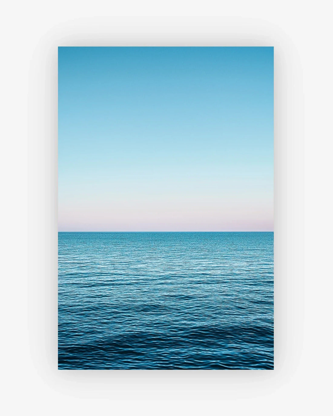Framed artwork of a blue ocean and sky with a white frame.