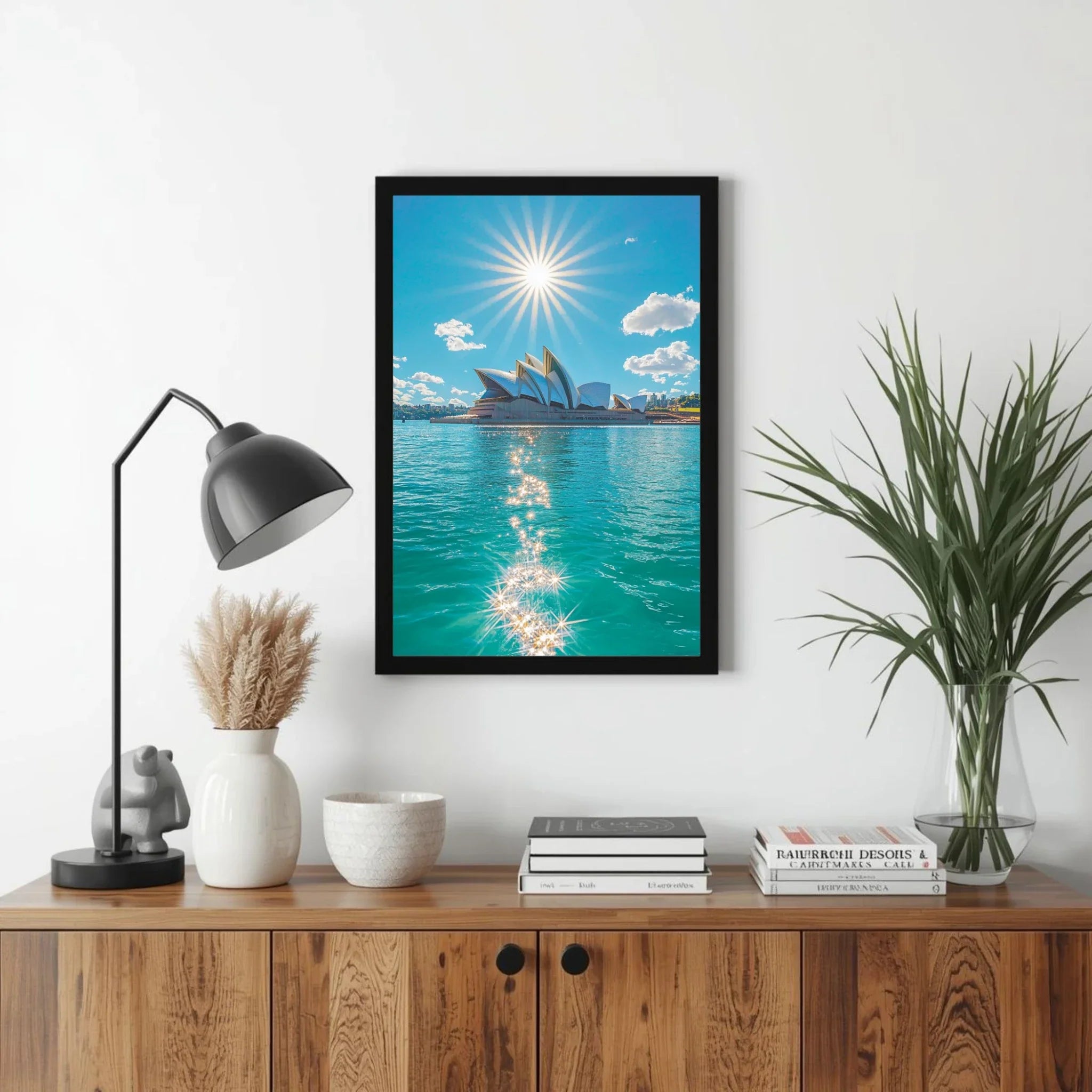Framed artwork of a city skyline with water and sun, displayed on a wall above a wooden cabinet.