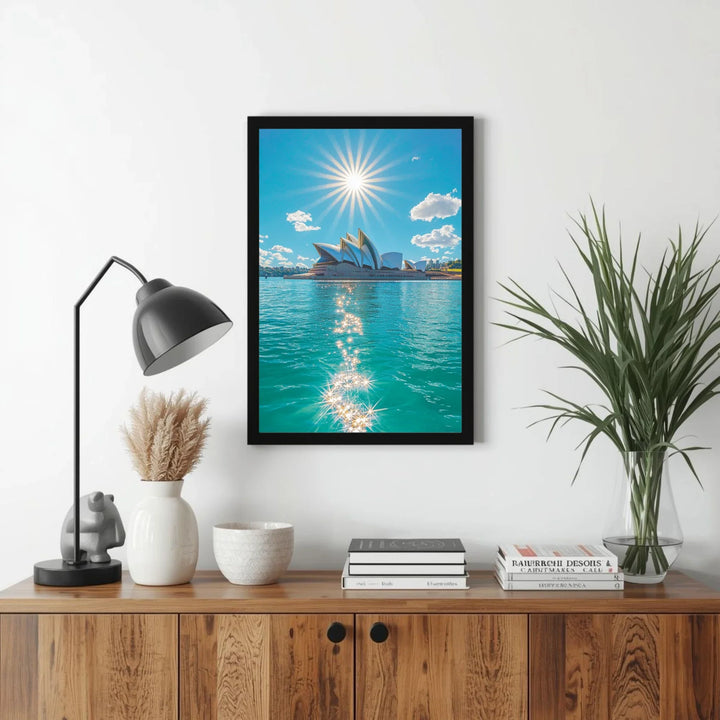 Framed artwork of a city skyline with water and sun, displayed on a wall above a wooden cabinet.