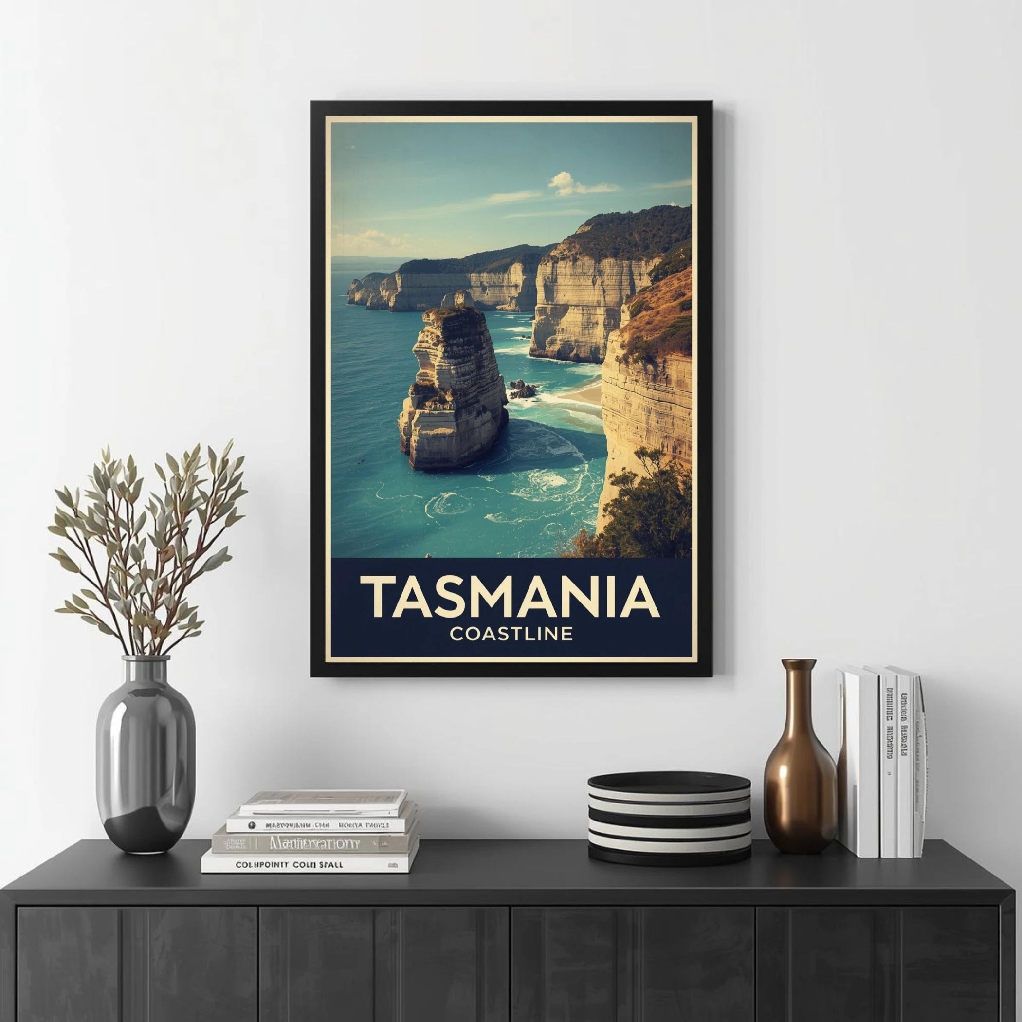 Framed poster of Tasmania coastline on a wall above a black cabinet with decorative items.