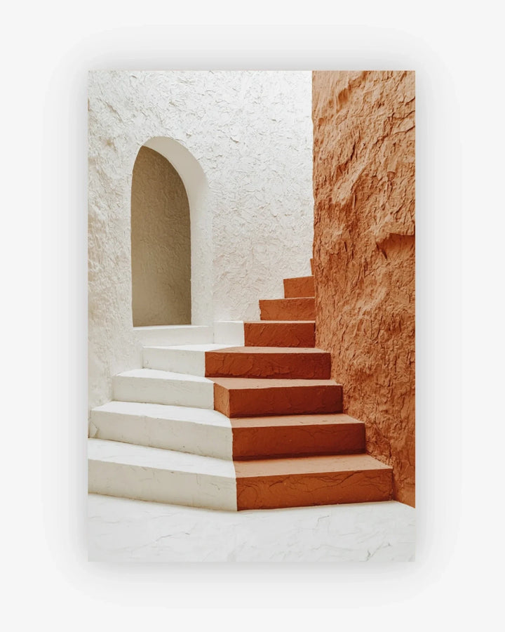 Staircase with white and red steps leading to an archway in a stone-walled building.