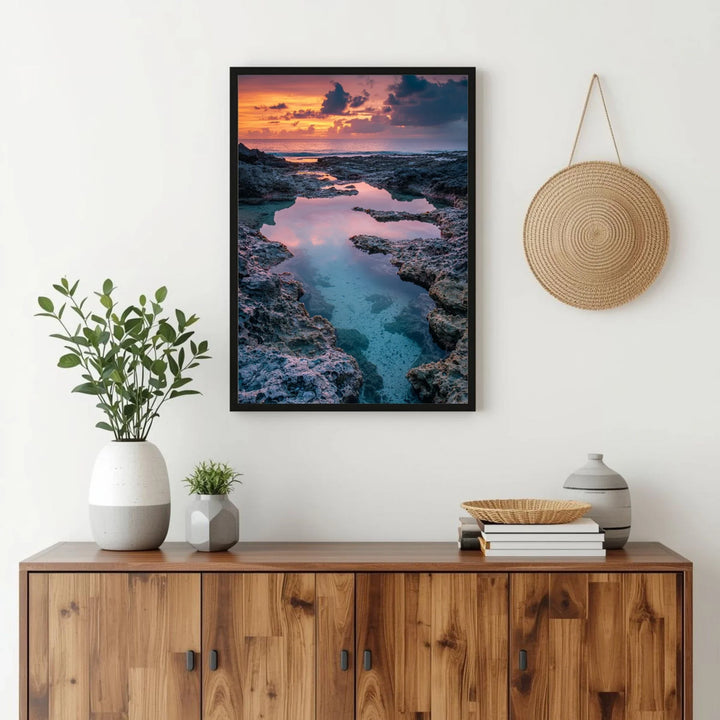 Room interior with wooden cabinet, framed artwork of a sunset over water, and decorative items.