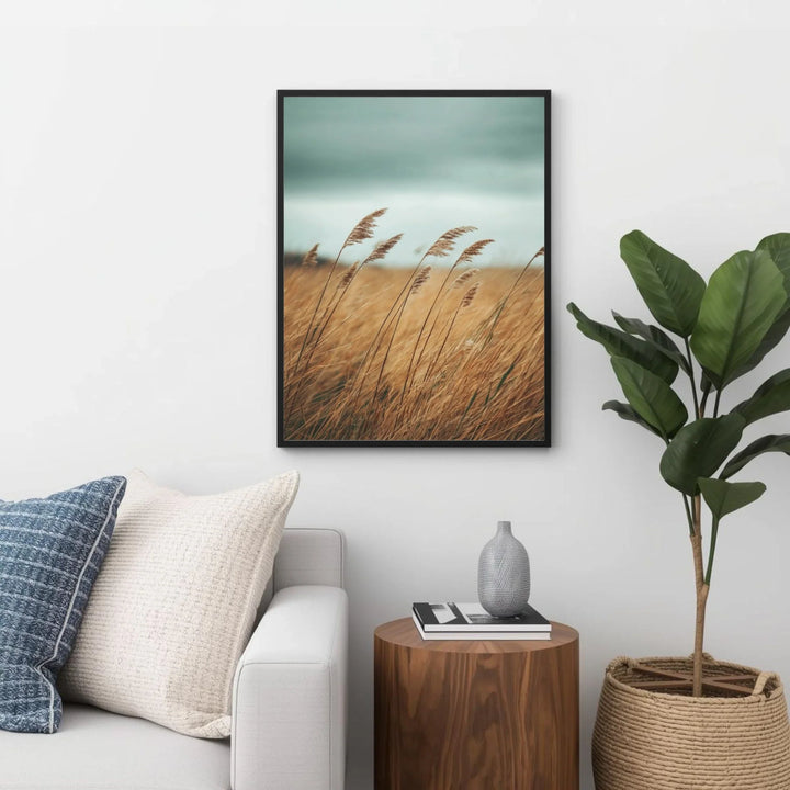 Framed artwork of a field with tall grass above a sofa and side table in a living room.