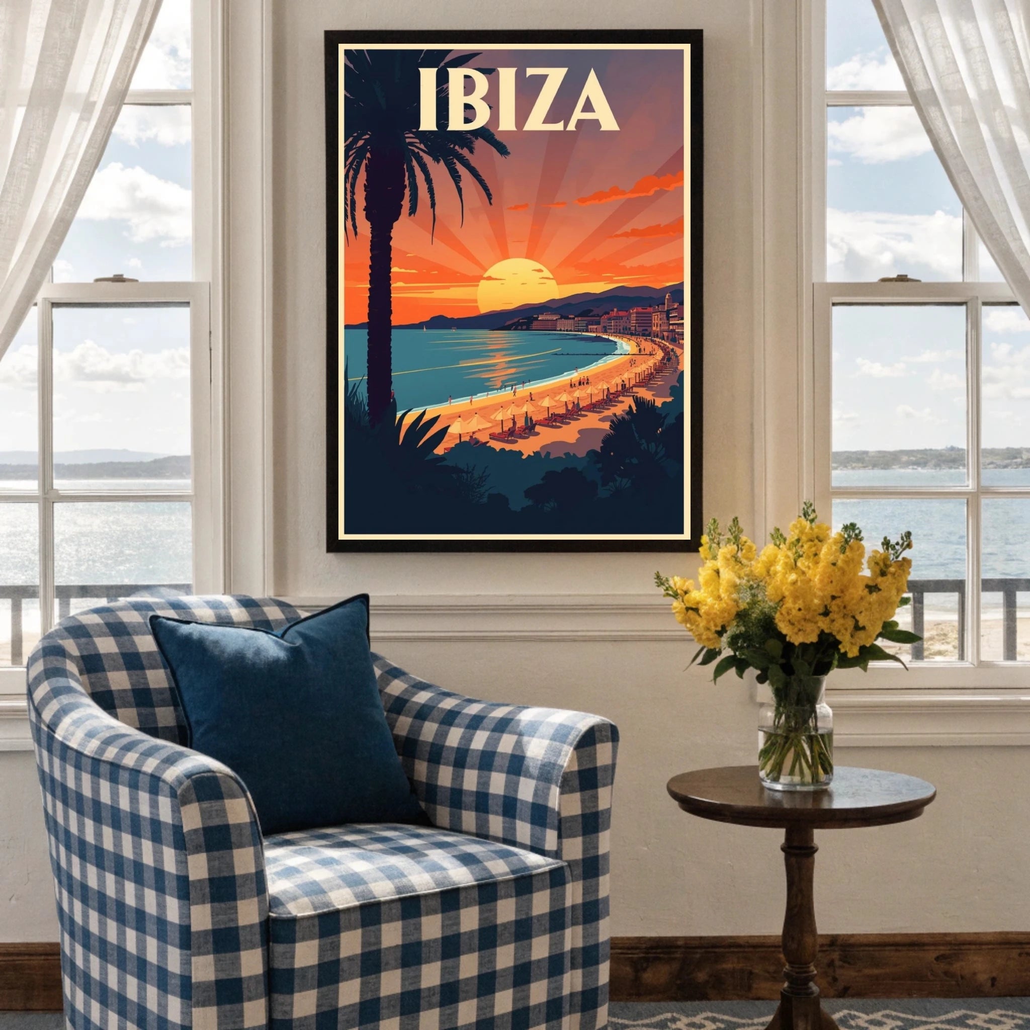 Framed poster of Ibiza on a wall above a checkered armchair with a table and flowers.