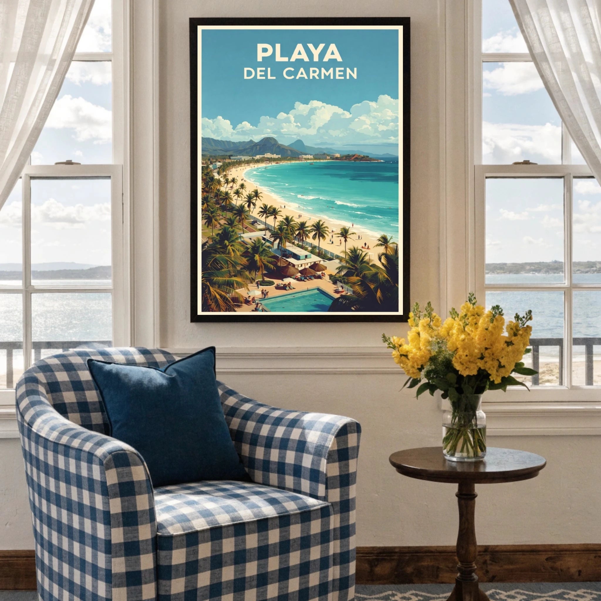 Framed artwork of Playa Del Carmen on a wall above a checkered armchair with a vase of yellow flowers.